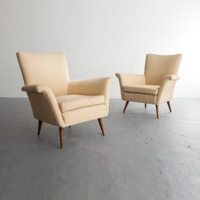 Pair of upholstered lounge chairs with turned hardwood legs.